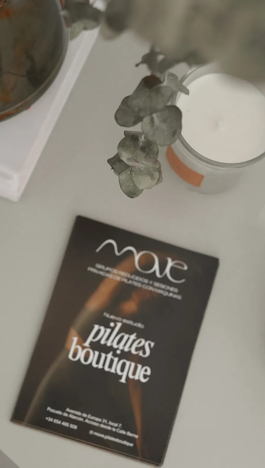 Tarjeta de MOVE Pilates Boutique junto a una vela y eucalipto